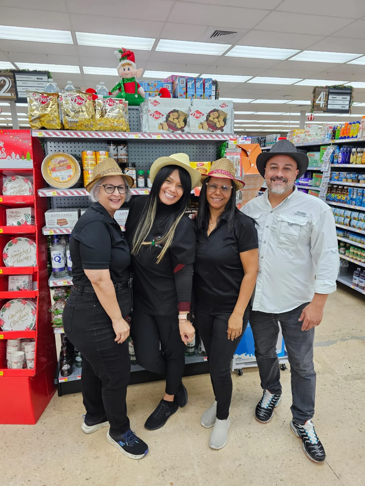 Cuatro miembros del equipo de Supermercados Agranel con sombreros en la sección Artesanía del País