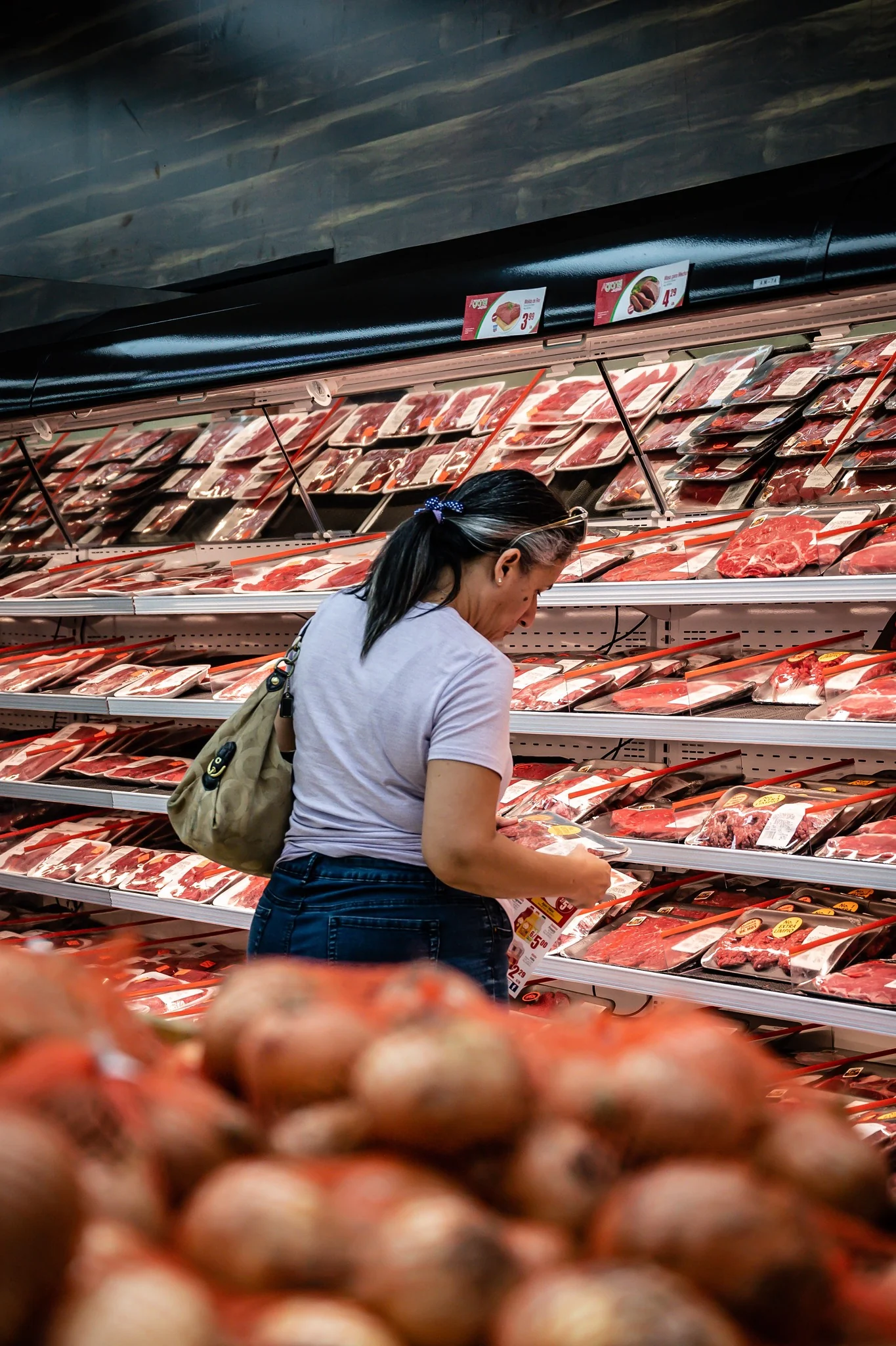 Clienta eligiendo carnes en la vitrina larga de Supermercados Agranel Pájaros
