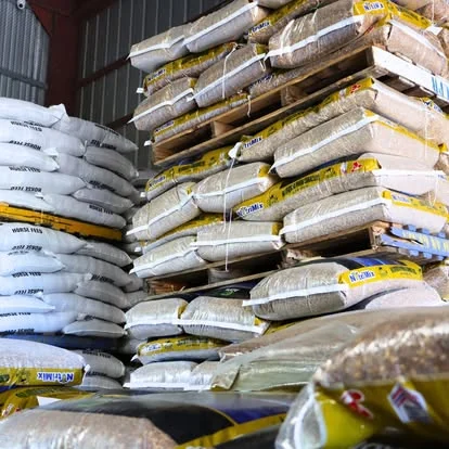 Almacén interior — sacos de Horse Feed y grano apilados en palé