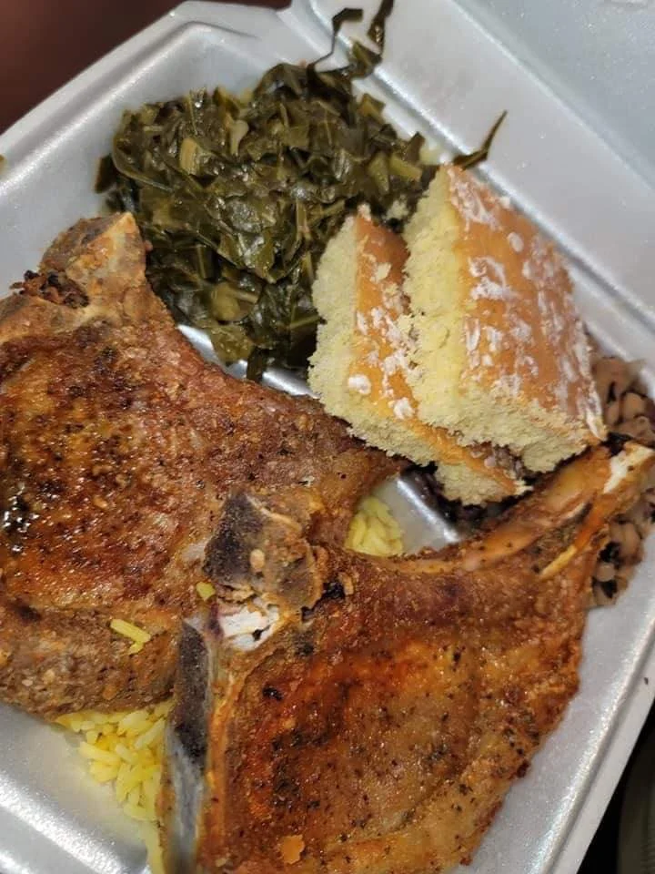 Chuletas de cerdo doradas sobre arroz amarillo con collard greens y pan de maíz