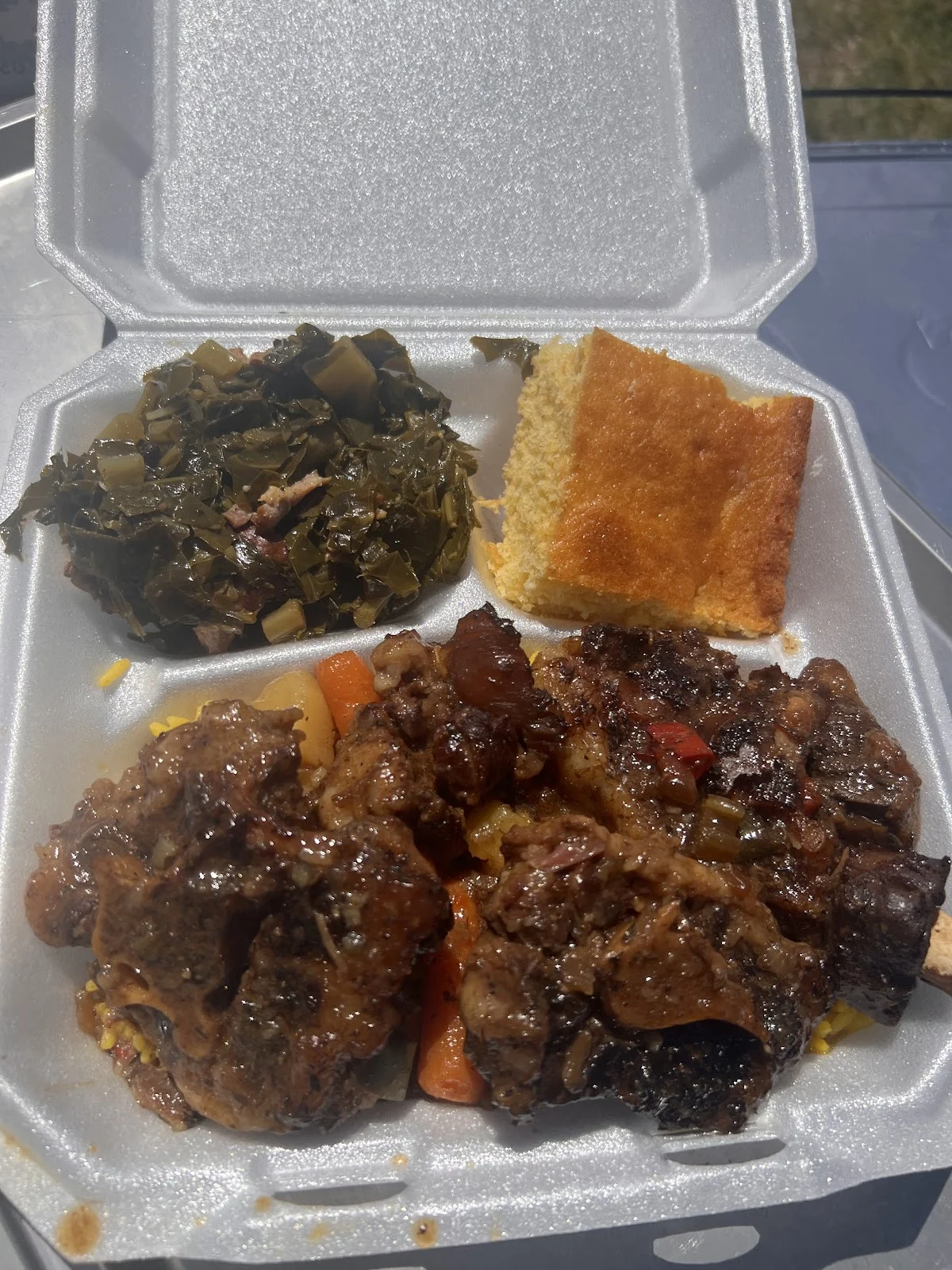 Oxtails guisados con zanahoria sobre arroz amarillo, collard greens y pan de maíz