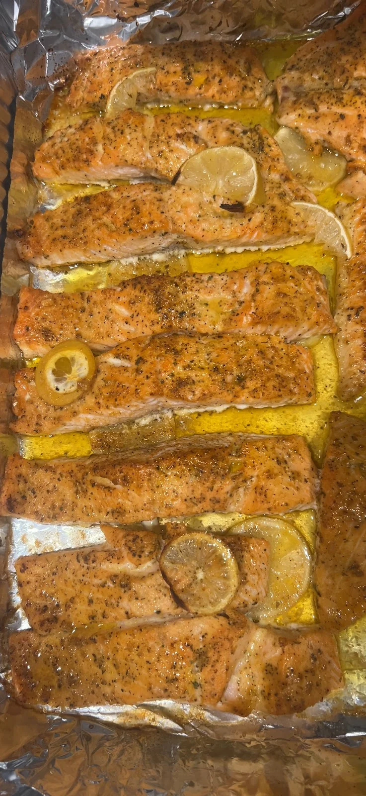 Bandeja de aluminio con filetes de salmón sazonados y rodajas de limón
