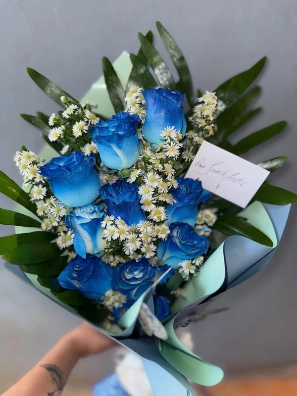 Ramo de rosas azules envuelto en papel menta con tarjeta escrita a mano