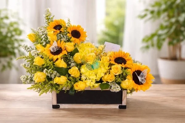 Caja de girasoles y rosas amarillas con mariposas decorativas