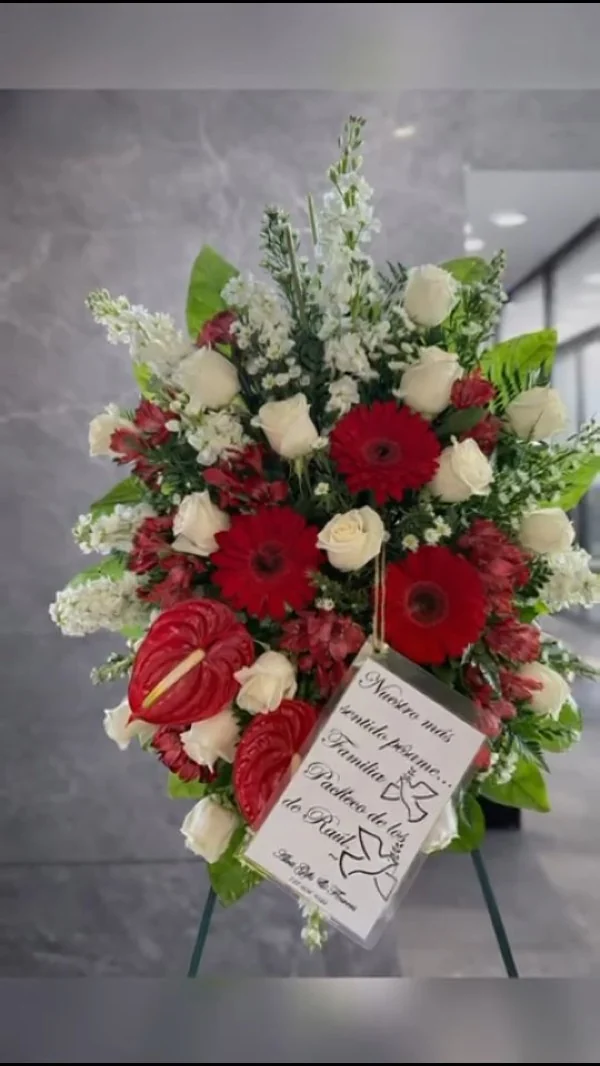 Corona fúnebre de gerberas rojas, anturios y rosas blancas con tarjeta de pésame