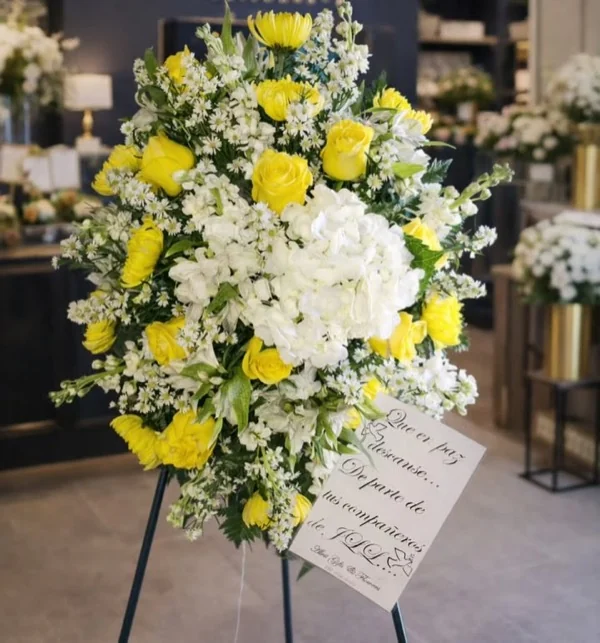 Corona de pie con rosas amarillas y hortensia blanca de parte de compañeros de trabajo
