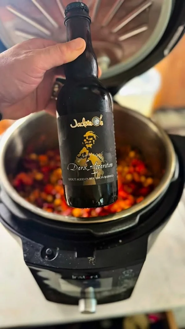 Vertiendo licor sobre la mezcla de arándanos y especias durante la elaboración del sirope