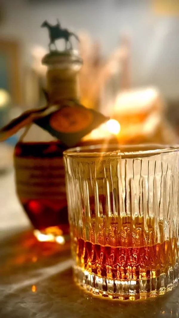 Cóctel servido en vaso tallado junto a una vela encendida