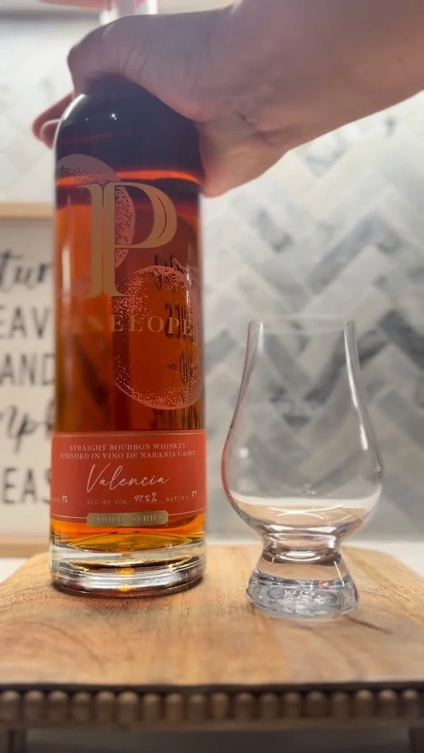 Botella de bourbon junto a una copa Glencairn de cata