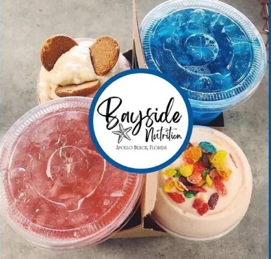 Four Bayside Nutrition cups in a carrier box: a wafer-topped shake, a blue loaded tea, a pink loaded tea and a shake topped with fruity cereal