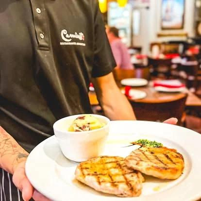 Mozo de Caminito llevando un plato de la parrilla al salón