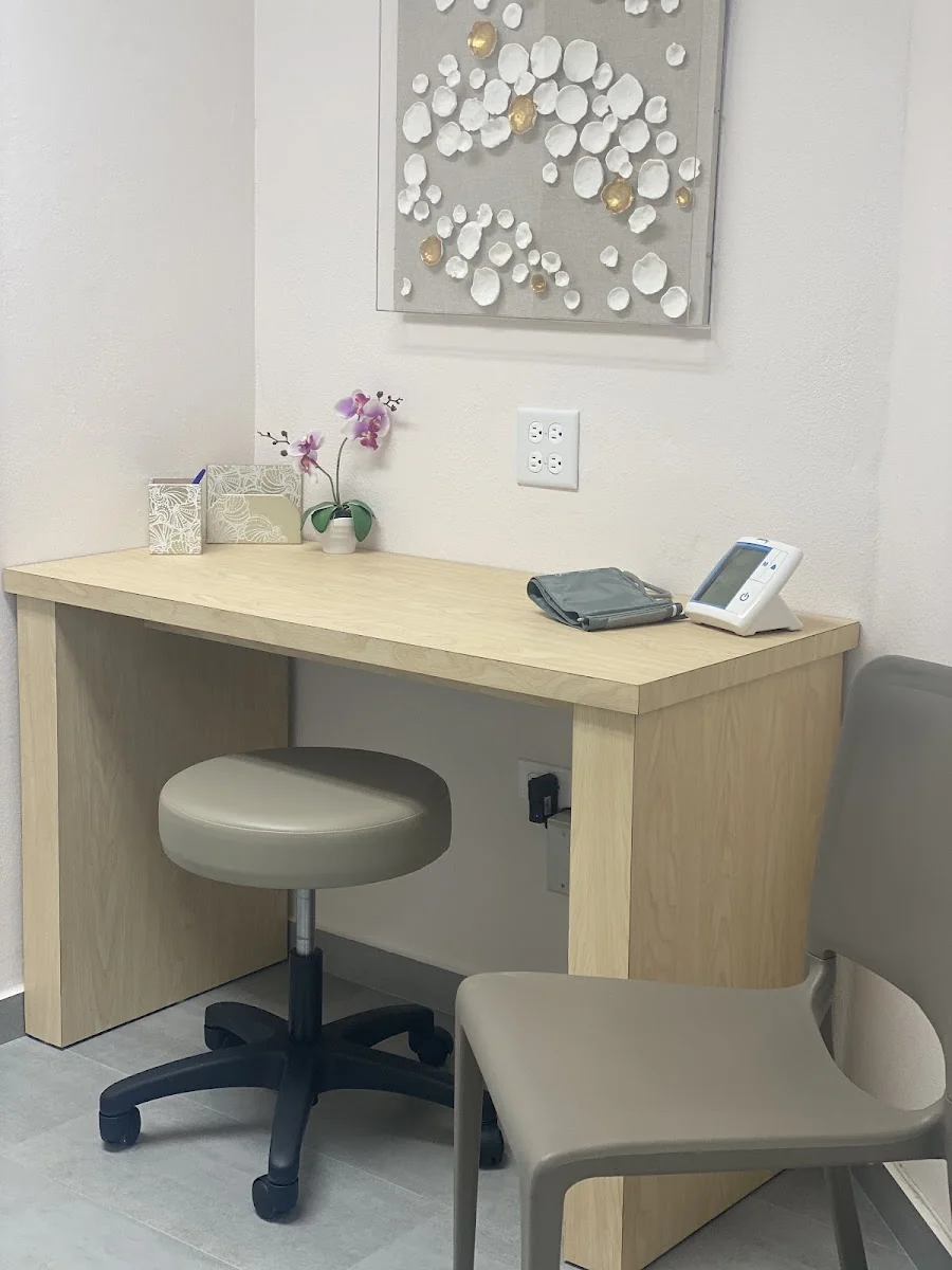 Sala de evaluación de Desalden Clinic con monitor de presión arterial y orquídea sobre el escritorio
