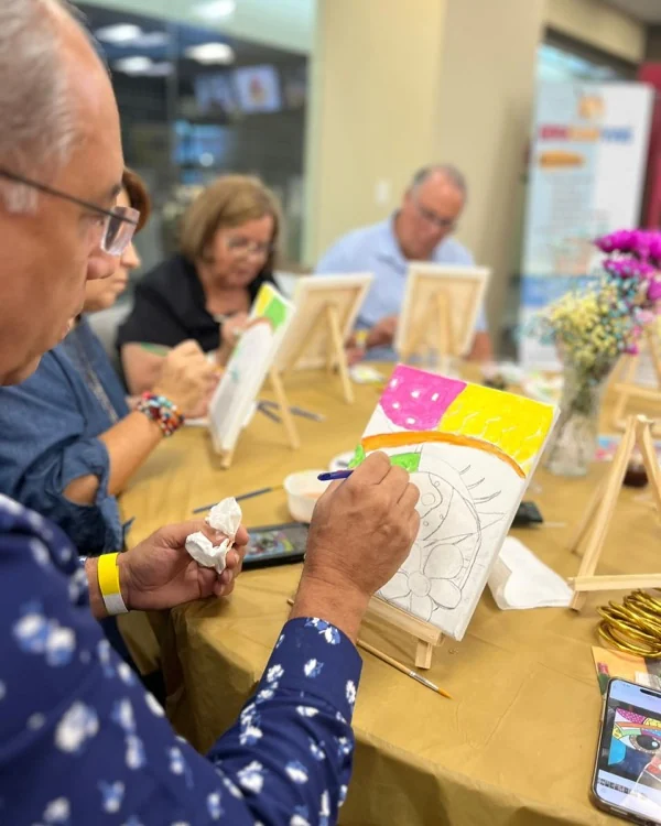 Adultos pintando lienzos en caballetes durante un taller grupal