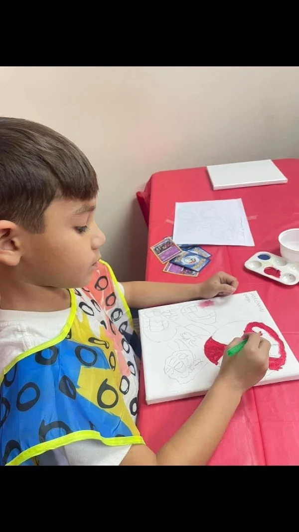 Niño pintando un lienzo con pintura roja en una clase de arte