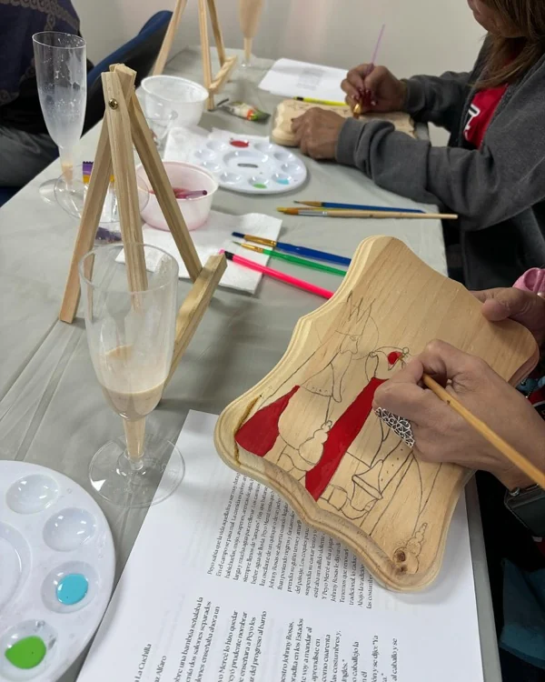 Manos pintando con pincel fino una pieza artesanal de madera