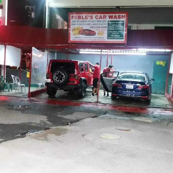 El equipo de Febles detallando un Jeep Wrangler rojo y un sedán azul de noche