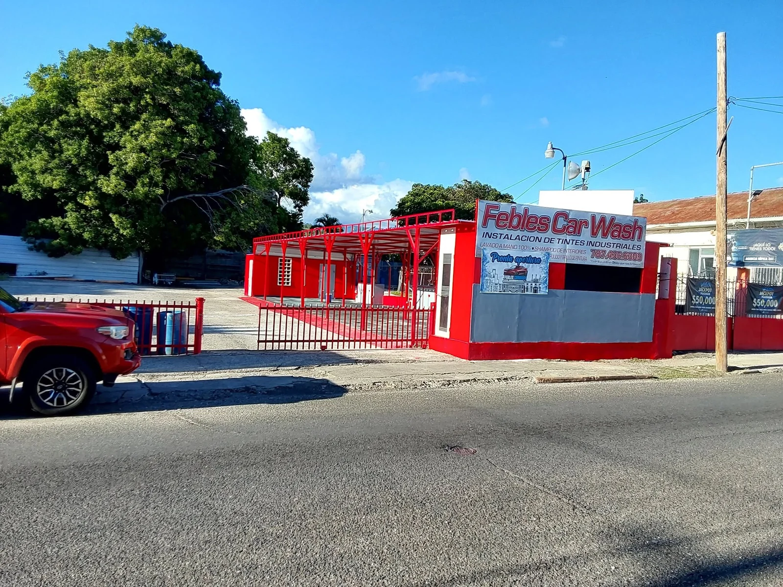 Fachada roja de Febles Car Wash con su letrero de lavado a mano y tintes industriales