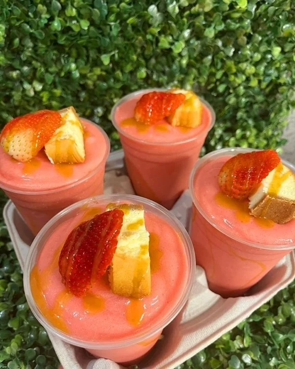 Bandeja con varios vasos de frappé de fresa decorados con fresa y bizcocho