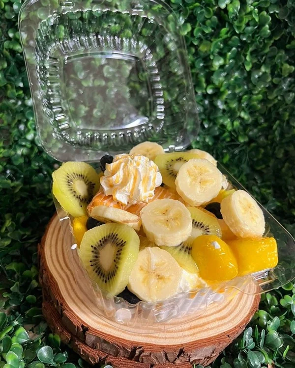Bowl con kiwi, guineo, mango y granola sobre base de madera