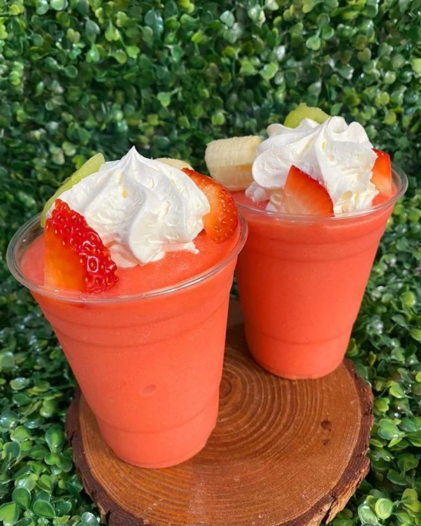 Dos frappés de fresa coronados con fresa, guineo y crema batida