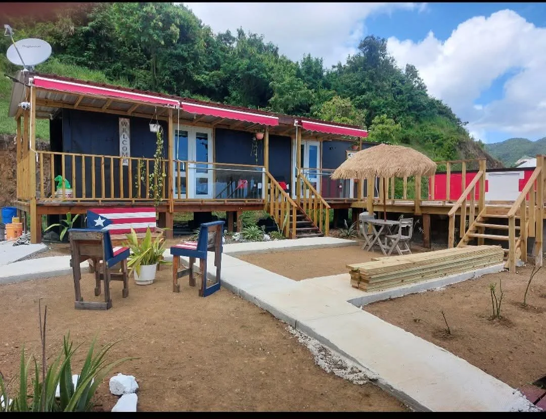 Cabañas de Hacienda Nereyda con terraza, sillas con la bandera de Puerto Rico y sombrilla tiki