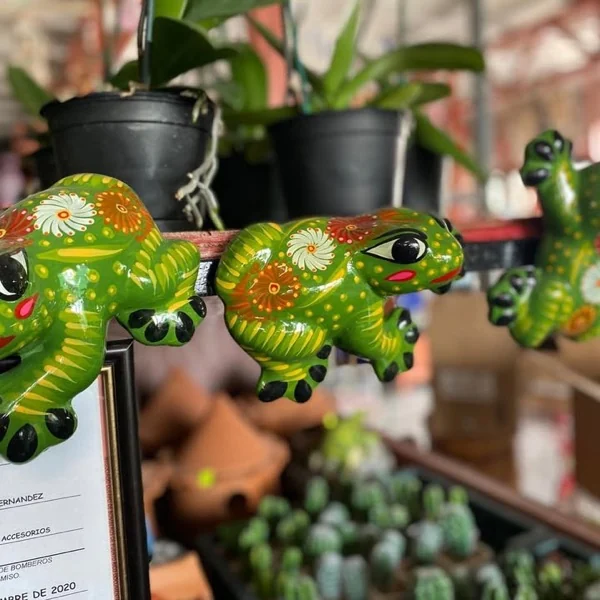 Ranas de cerámica pintadas a mano en verde sobre una repisa del vivero