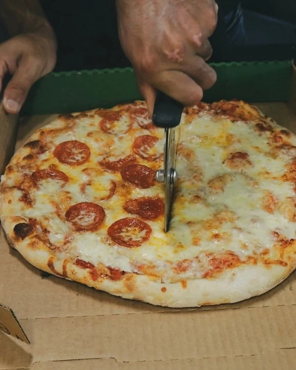 Cortando la pizza recién salida del horno