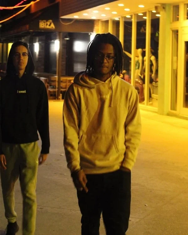 Dos personas de noche en la calle, una con hoodie JUNZI color arena y otra con hoodie negro