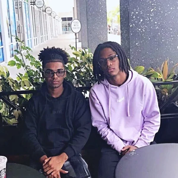 Dos amigos sentados, uno con hoodie JUNZI lila y otro con hoodie negro