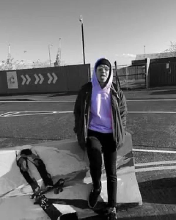 Persona con hoodie JUNZI lila y patineta, con el resto de la foto en blanco y negro