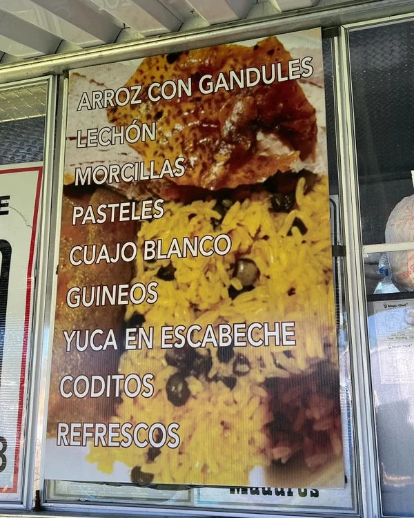 El menú de la Lechonera Pagán pintado en la ventana del trailer: arroz con gandules, lechón, morcillas, pasteles, cuajo blanco, guineos, yuca en escabeche, coditos y refrescos