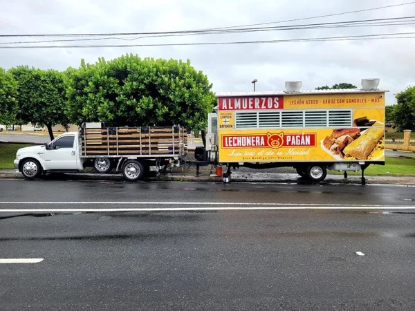El trailer de Lechonera Pagán remolcado por la carretera de Bayamón con el lema Algo todo el año es Navidad en el rótulo