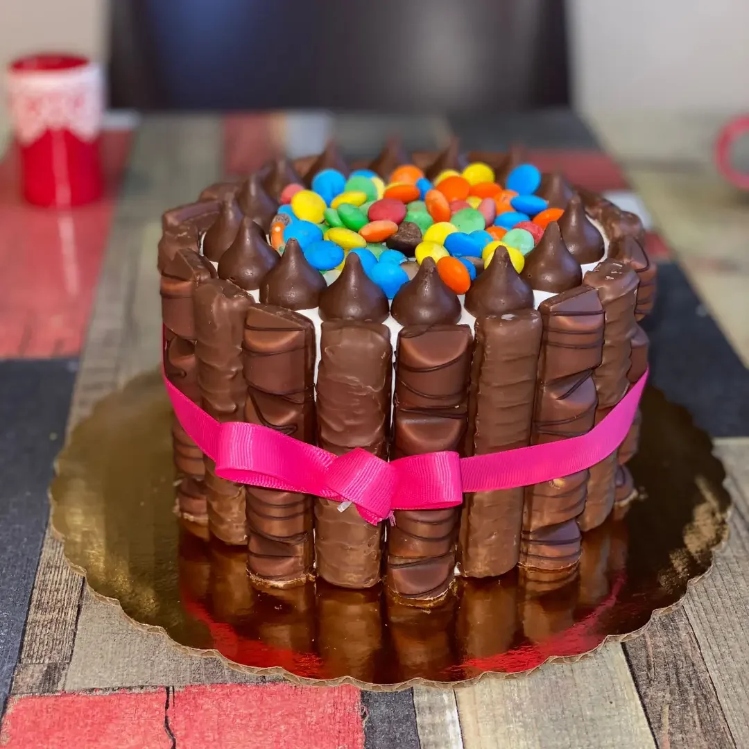 Bizcocho decorado por encargo con chocolates y lazo rosa