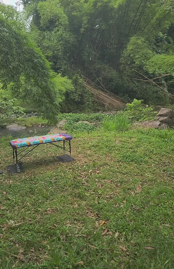 Camilla de masaje colocada en un claro del bosque junto a un río, entre bambúes