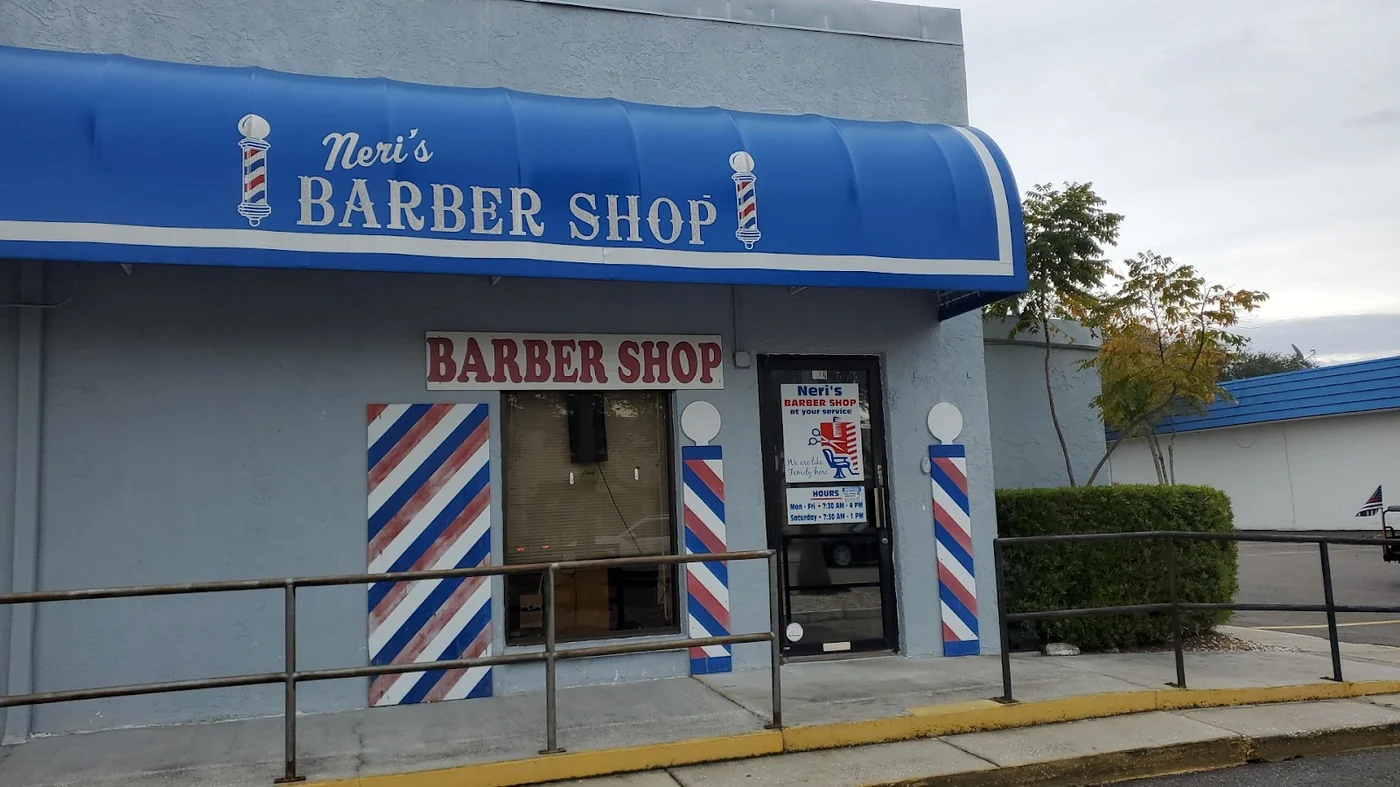 Entrada de Neri's Barber Shop con postes de barbero