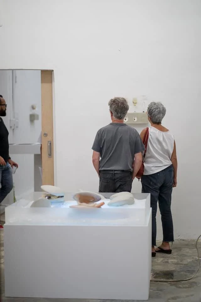 Público observando piezas escultóricas sobre pedestal blanco durante una apertura en Recinto Cerra