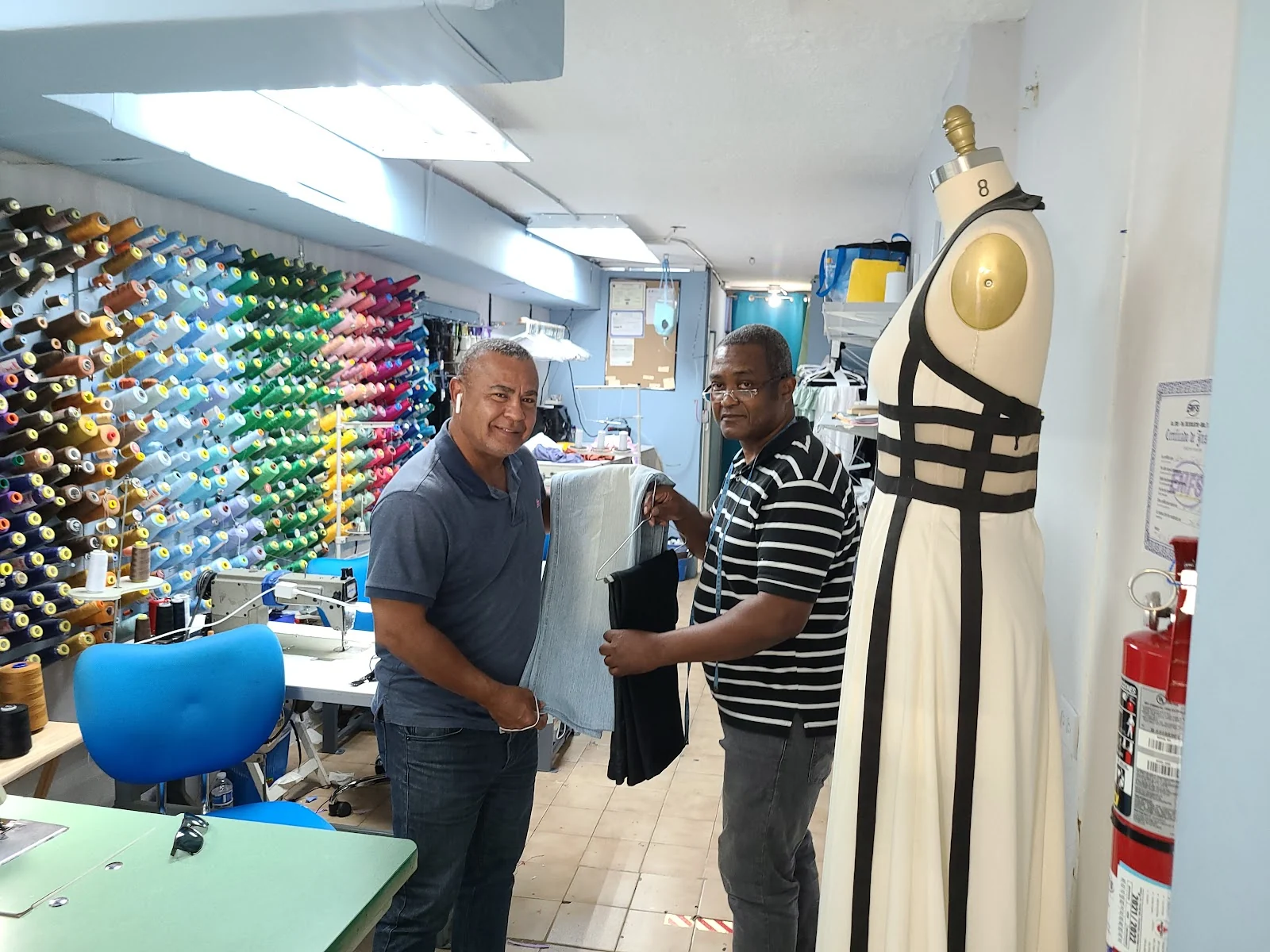 Interior de Sastrería Santos: pared de carretes de hilo de colores y maniquí con vestido