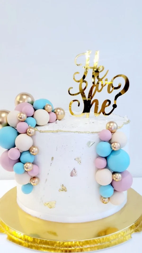 Cake de gender reveal con topper dorado He or She y globos pastel