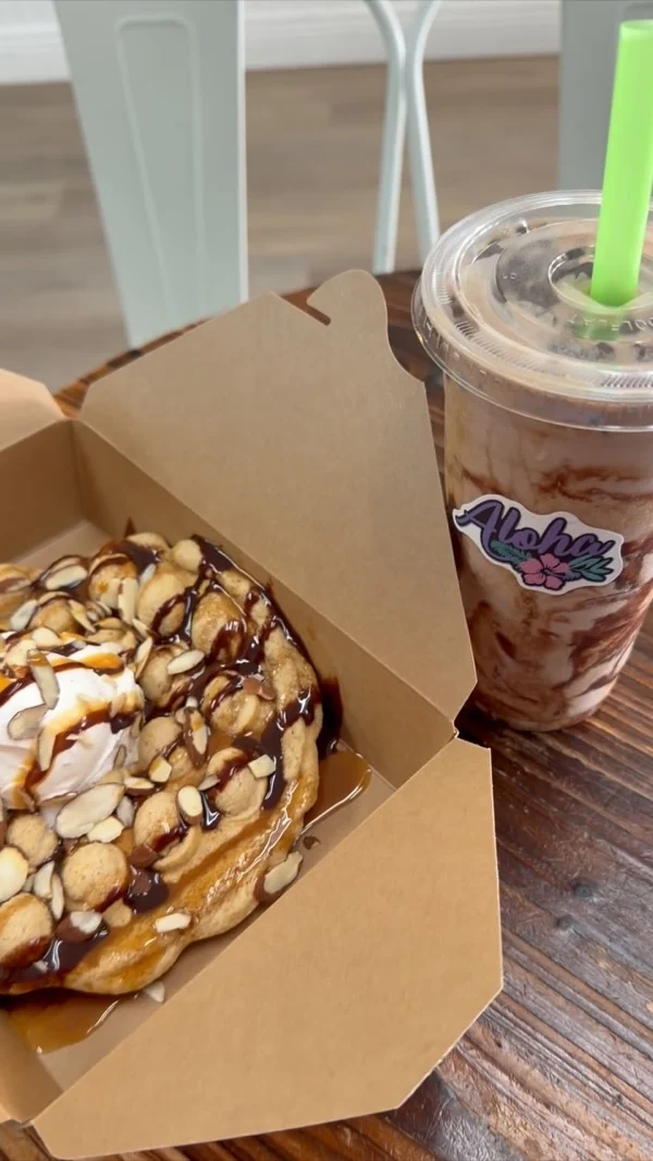 Protein treat con drizzle de chocolate y almendras en caja kraft, junto a un coffee batido
