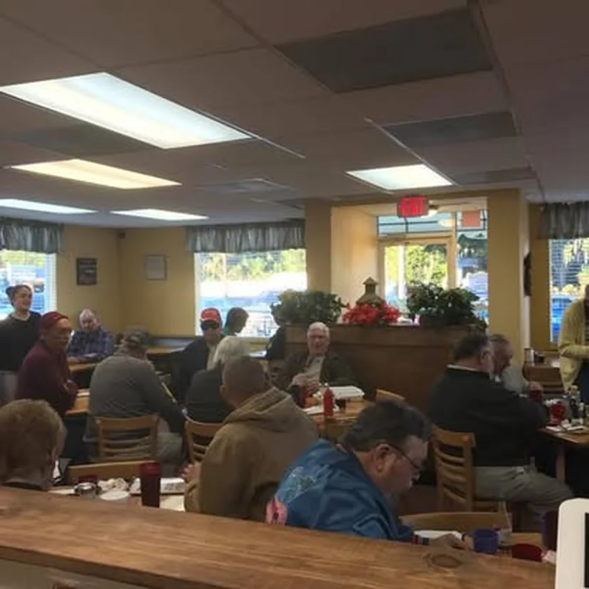 Comedor de Kountry Kitchen lleno de clientes junto a la mesa corrida de madera