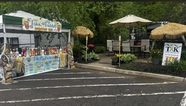 Toldo de Tiki Turbo montado en un estacionamiento con la barra de smoothies, tótems tiki y sombrillas de paja